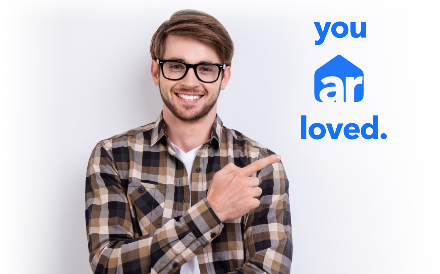 man in glasses and plaid shirt pointing at trademark branding logo 'you ar loved'