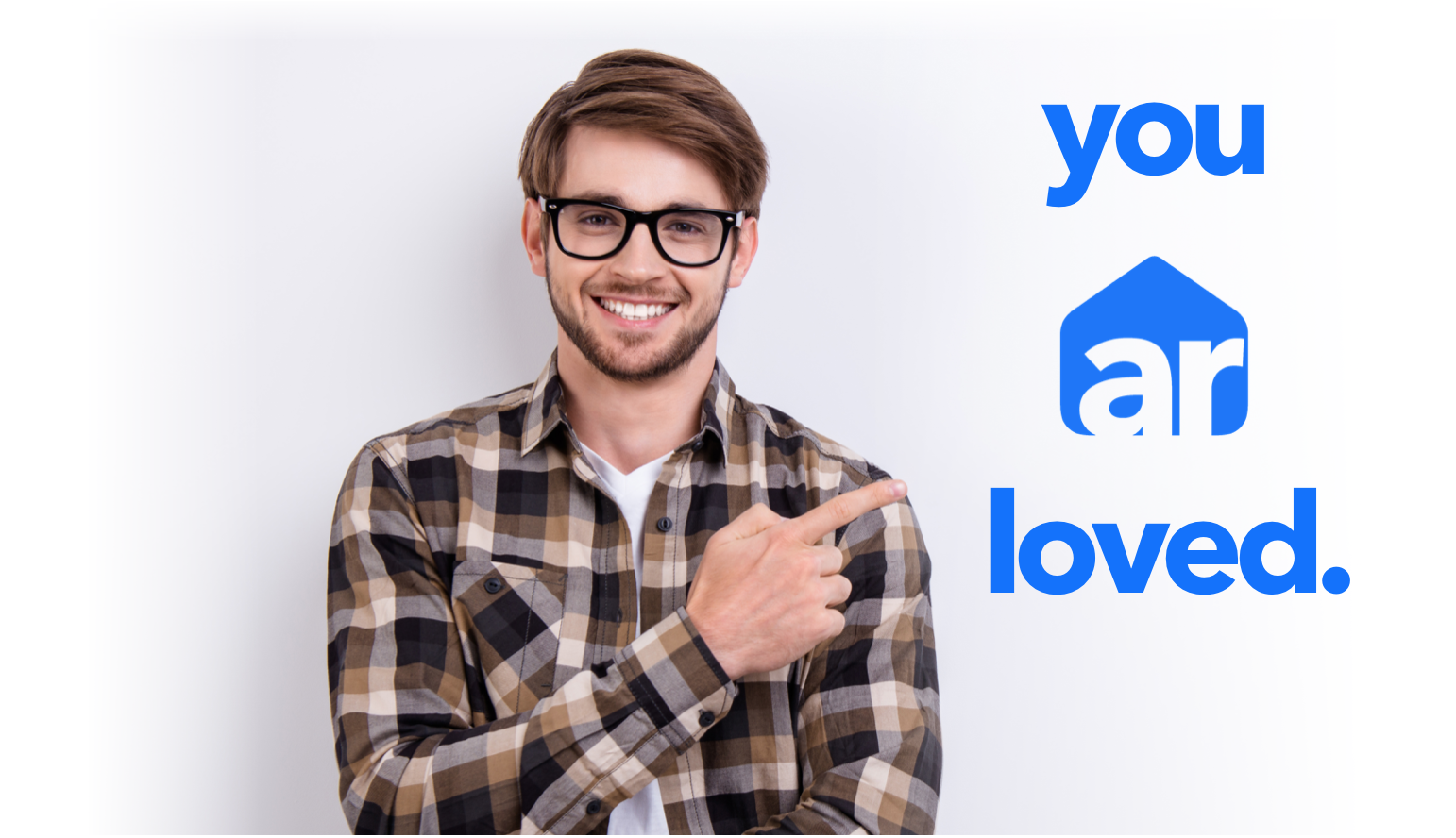man in glasses and plaid shirt pointing at 'you ar loved' trademark branding logo