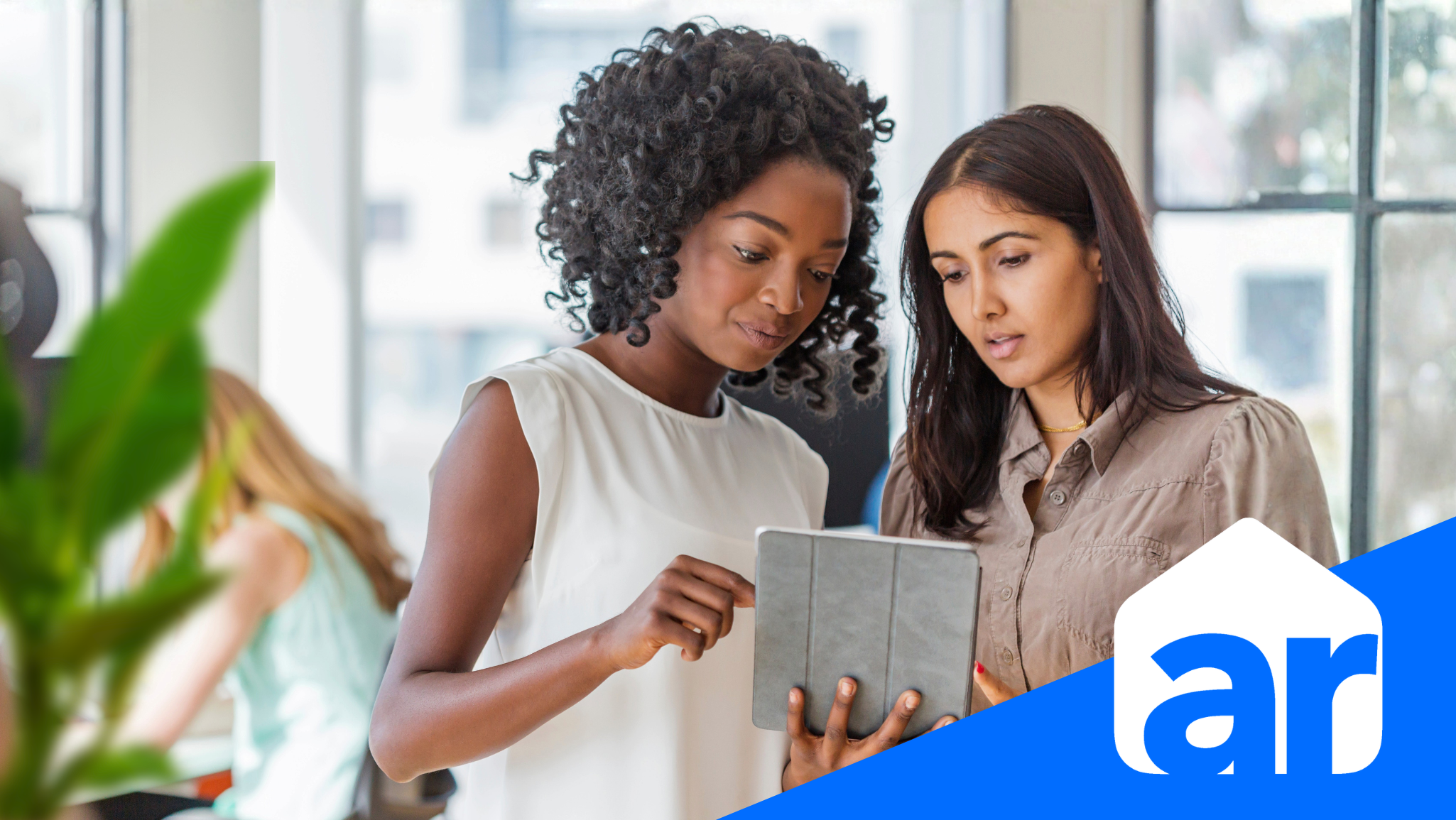 two women talking and looking at an ipad