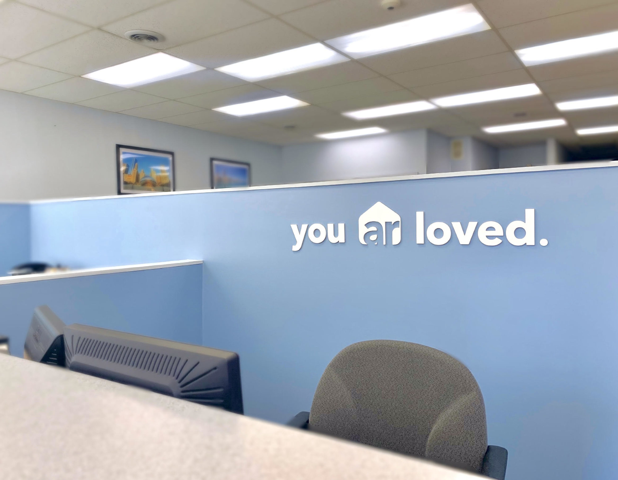 photo of the front desk at arhome realty with the sign on the wall 'you ar loved'